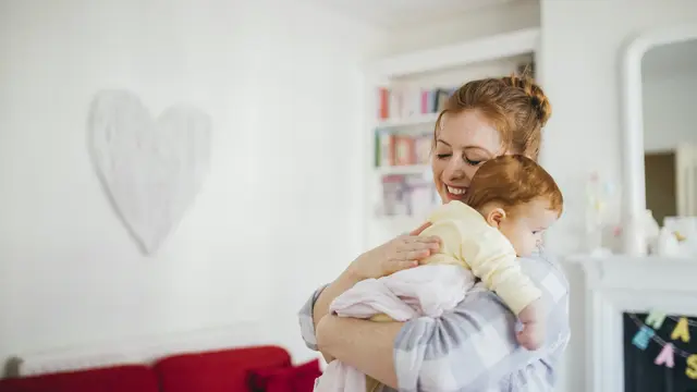 Mutter hält Baby im arm und kuschelt