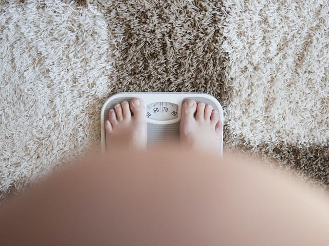 Schwangere Frau wiegt sich während der Schwangerschaft mit Bauch im Bild