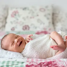 Baby liegt strahlend und lachend im Bett