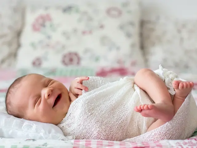 Baby liegt strahlend und lachend im Bett