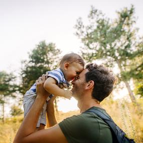 Mann mit Baby im Arm kuschelt Baby in Umgebung der Natur