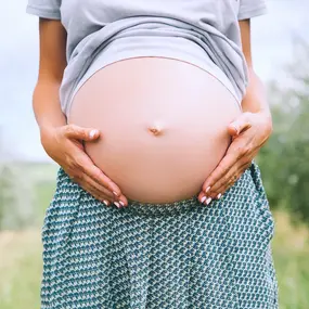 Schwangere Frau in der Natur hält Ihren Bauch