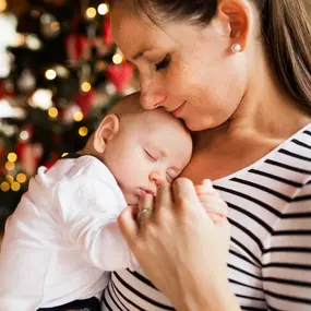 Frau vor Weihnachtsbaum mit Baby