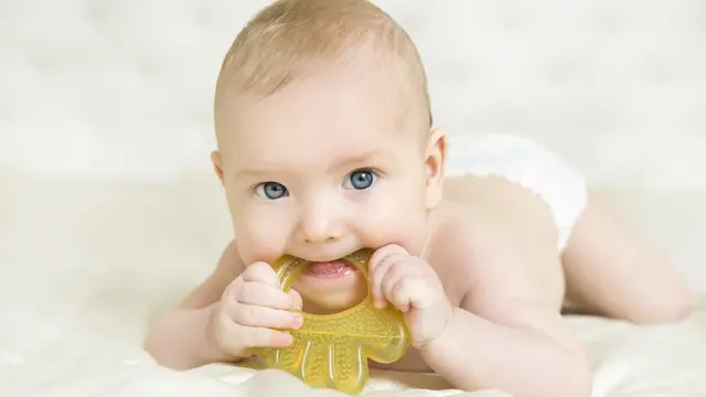 Baby mit Spielzeug lacht in die Kamera