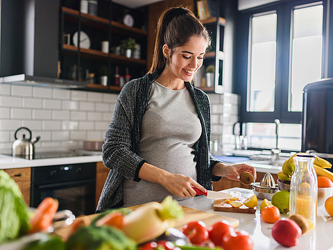 Schwangere bereitet Salat zu