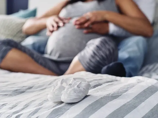 Schwangere Frau auf dem Sofa hält sich Bauch