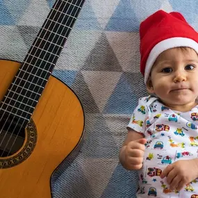 Baby liegt mit Gitarre auf dem Boden