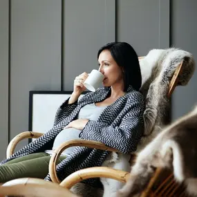 Frau sitzt entspannt auf dem Sofa und schaut raus.