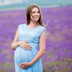 Schwangere Frau auf dem Feld hält Ihren Bauch