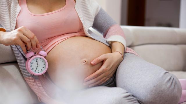 Schwangere Frau mit Uhr - Geburtsrechner