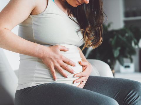 Schwangere Frau hält Bauch bei Beschwerden