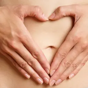 Frau mit Kinderwunsch hält Herz Hand an den Bauch
