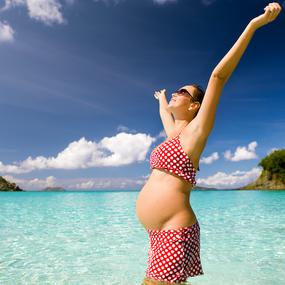 Schwangere Frau freudig am Strand