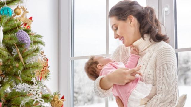 Frau an Weihnachten mit Baby im Arm