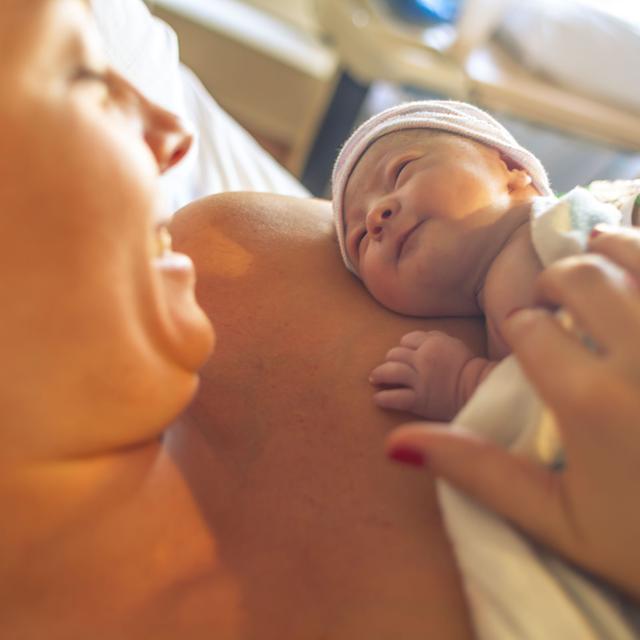 Person kuschelt mit neugeborenem Baby (nicht klar ob Mann oder Frau)