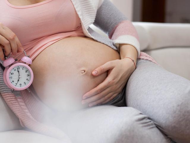 Frau sitzt auf dem Sofa mit Countdown zur Entbindung