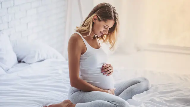 Schwangere Frau auf Bett hält Bauch