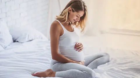 Schwangere Frau auf Bett hält Bauch