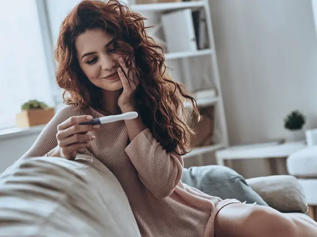 Frau mit Schwangerschaftstest auf dem Sofa