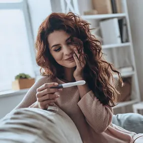 Frau mit Schwangerschaftstest auf dem Sofa