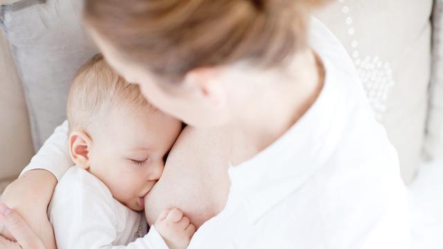 Frau stillt Baby im Arm