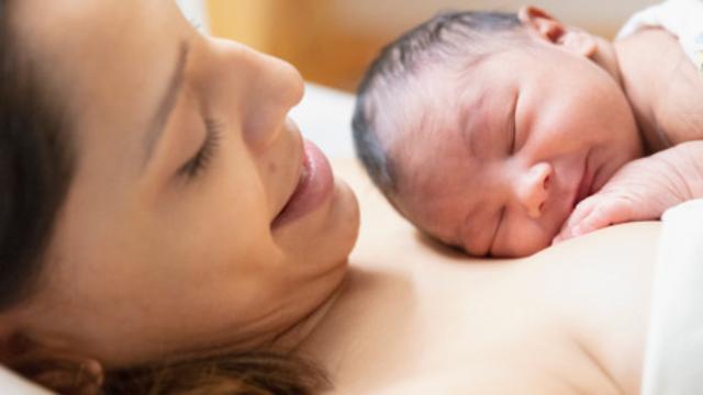 Schwangere Frau liegt mit Baby auf der Brust