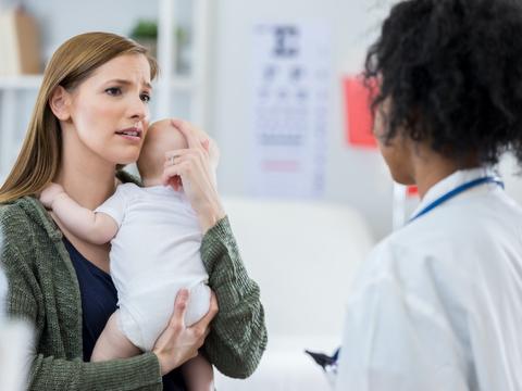 Mutter beim Arzt mit Baby auf dem Arm