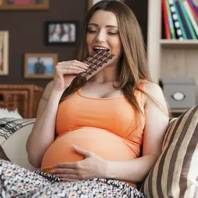 Schwangere Frau essend und hält sich den Bauch