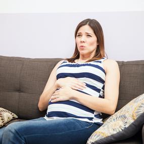 Schwangere Frau mit Wehen auf dem Sofa