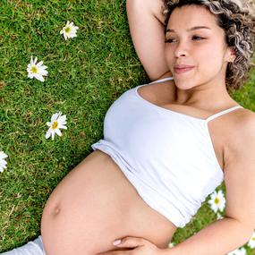Schwangere Frau liegt in Blumenwiese 