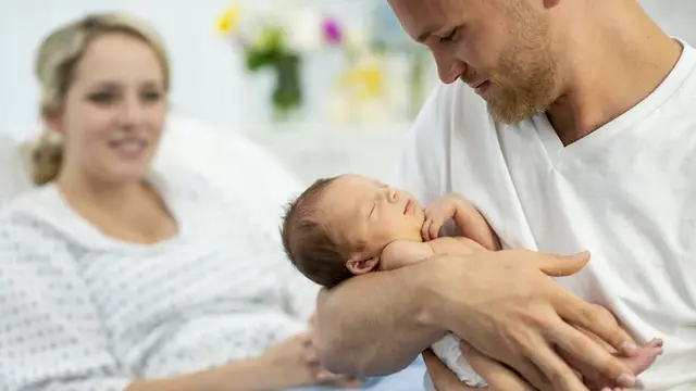 Vater hält neugeborenes im Arm