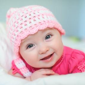 Baby mit Mütze lacht in Kamera