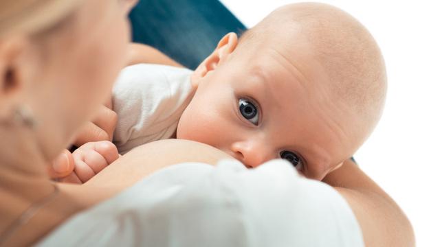Mutter stillt Baby im Arm mit Blick in die Kamera