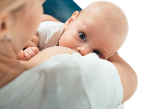 Mutter stillt Baby im Arm mit Blick in die Kamera