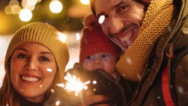 Glückliche Familie mit Baby im Arm an Silvester